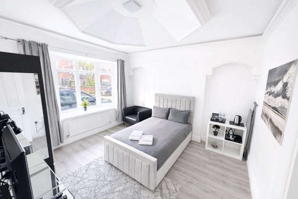 a white bedroom with a bed and a window at The Villas in Rock Ferry