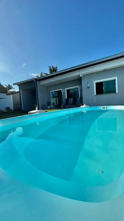 a large blue swimming pool in front of a house at Casa de praia em Barra do Gil in Vera Cruz de Itaparica