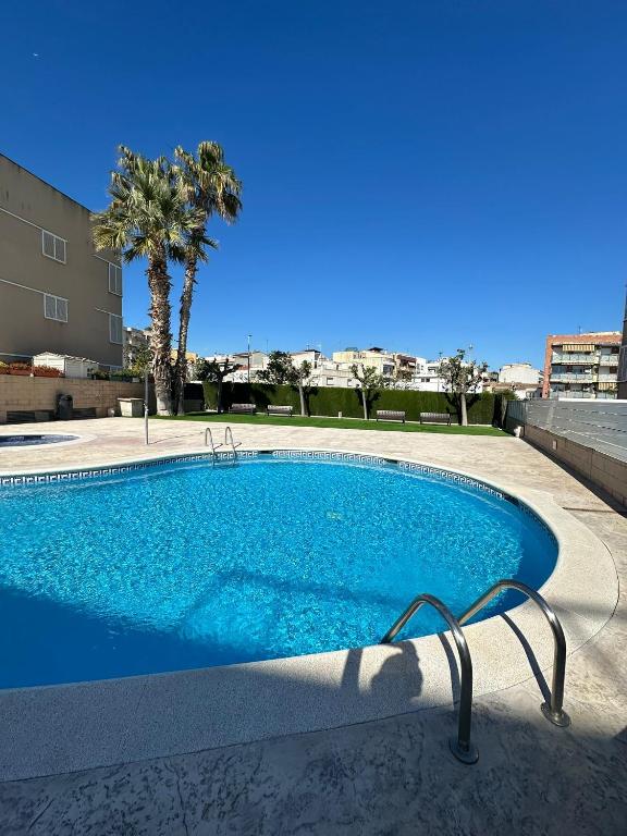 a blue swimming pool with a palm tree in the background at Comfort home Calafell in Calafell