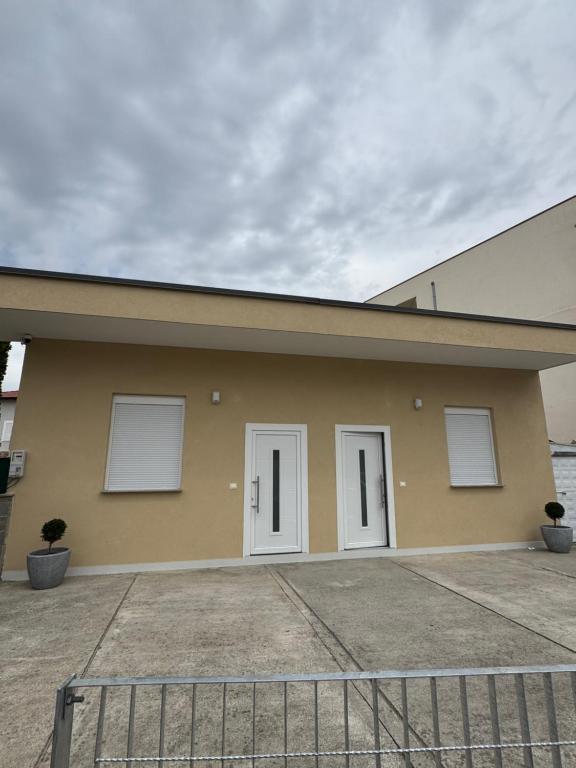a yellow building with three white doors on it at Aron apartments in Tirana