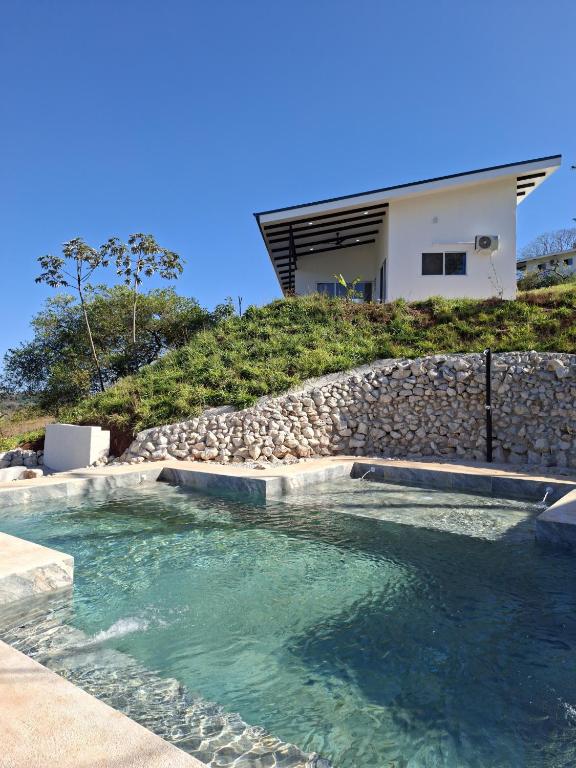 a swimming pool in front of a house at Pura Vista Lodge in Sámara