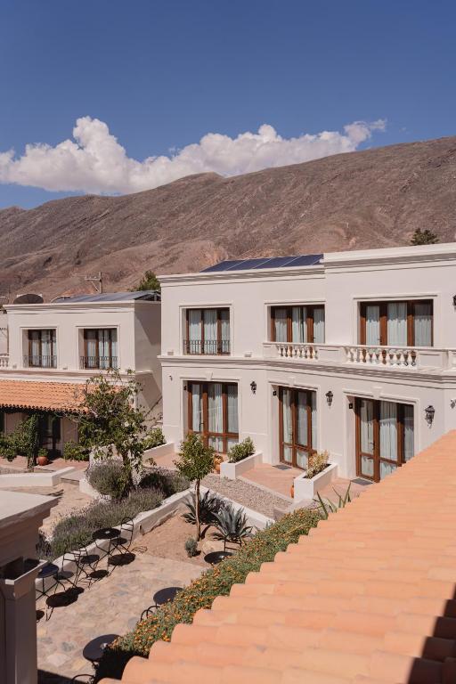 a large white building with a mountain in the background at Hotel El Candil Tilcara in Tilcara