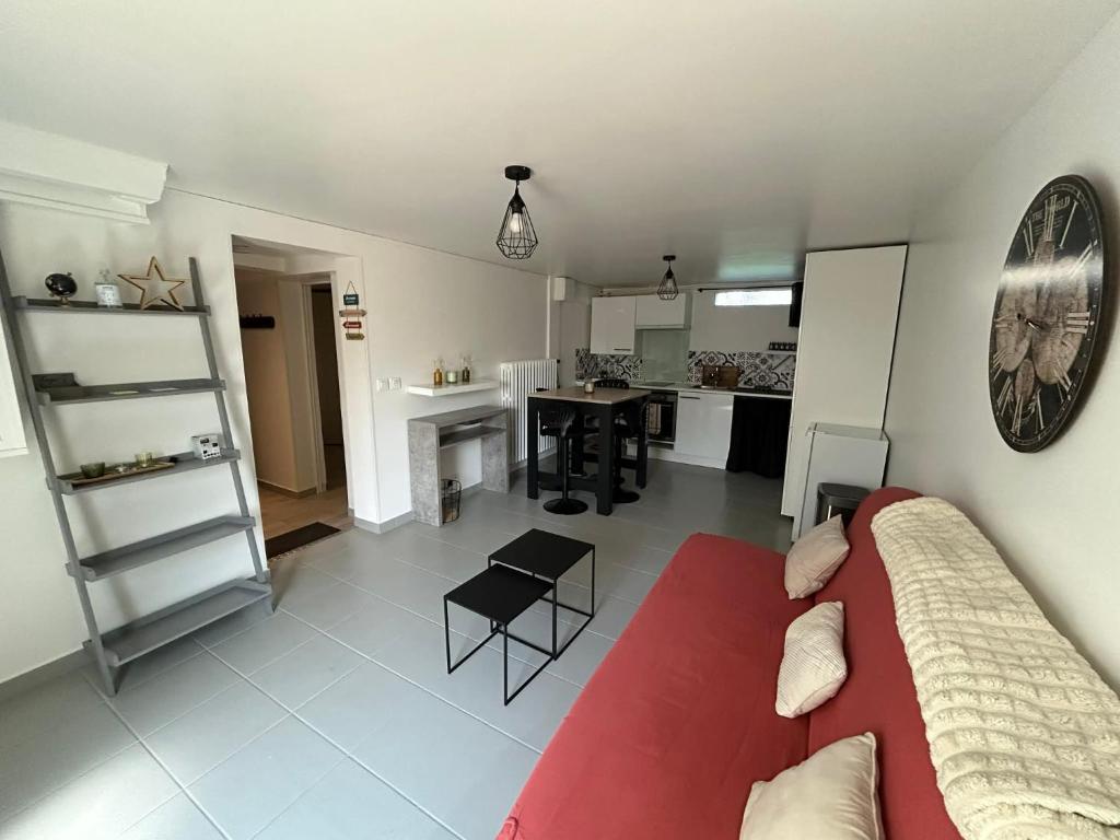 a living room with a red couch and a kitchen at Le studio de Louisette in Châteaudun