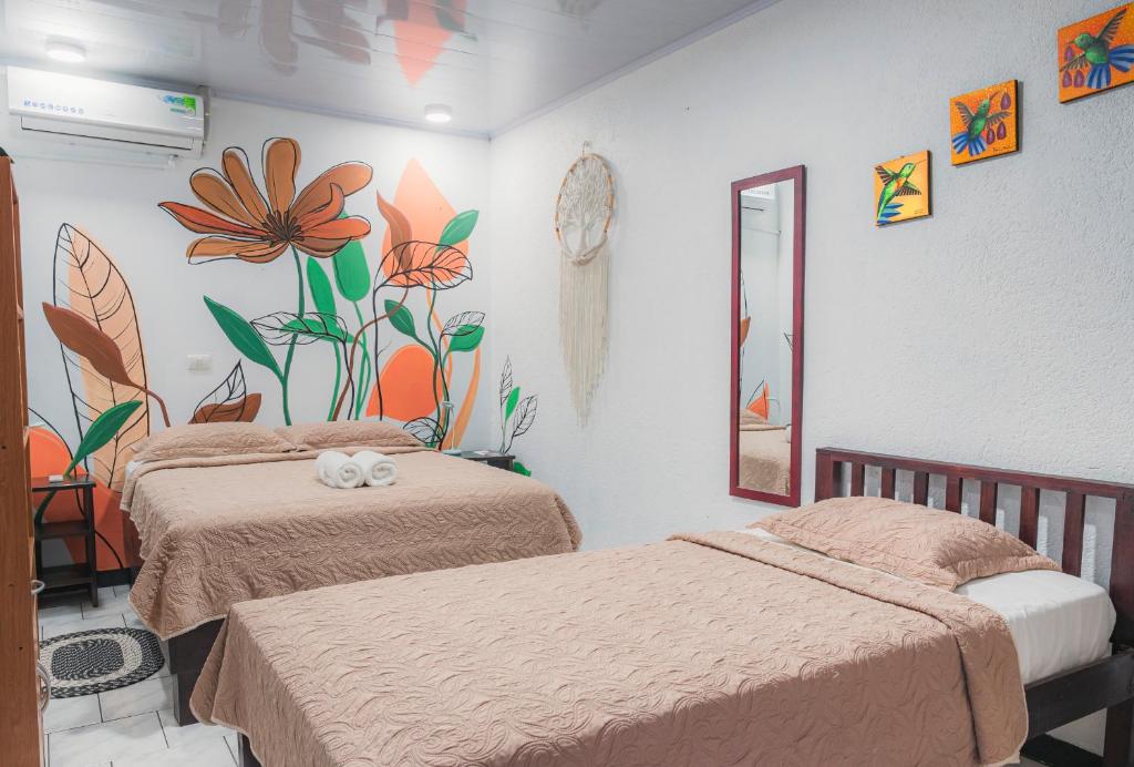 a bedroom with two beds and a flower mural on the wall at Red Frog Rooms in Fortuna
