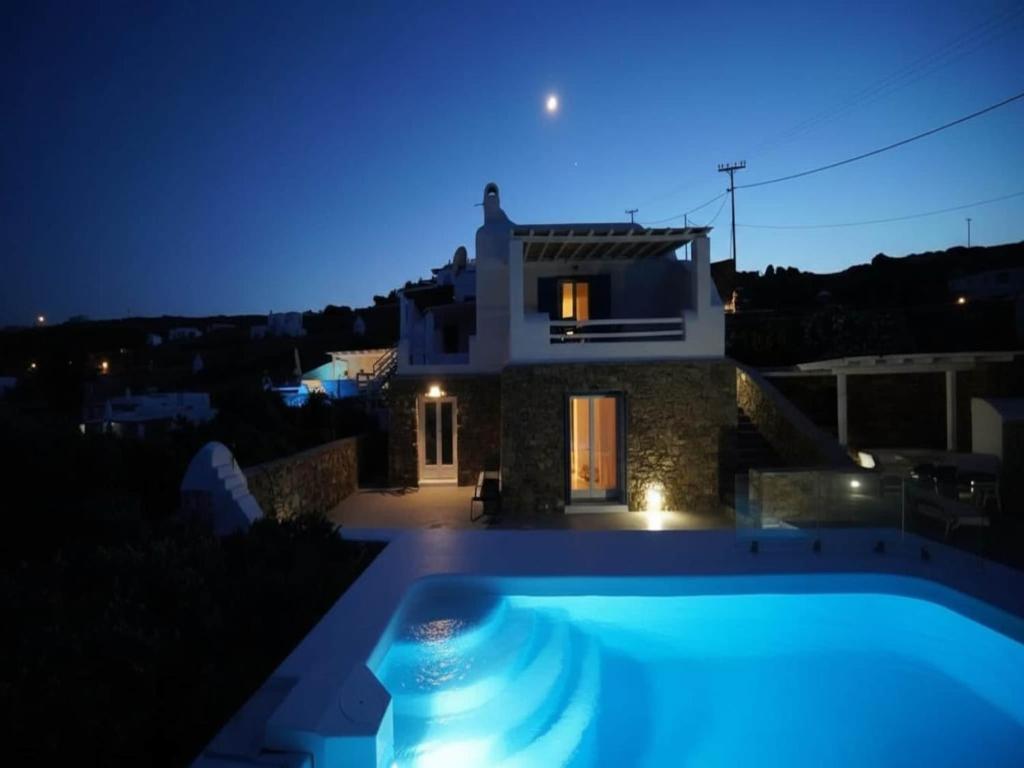 a villa with a swimming pool at night at Panormos Stay for Seven Guests in Mikonos