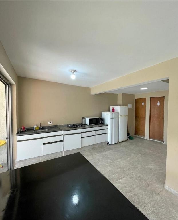 a large kitchen with white cabinets and a refrigerator at Estância 7 praias in São Paulo