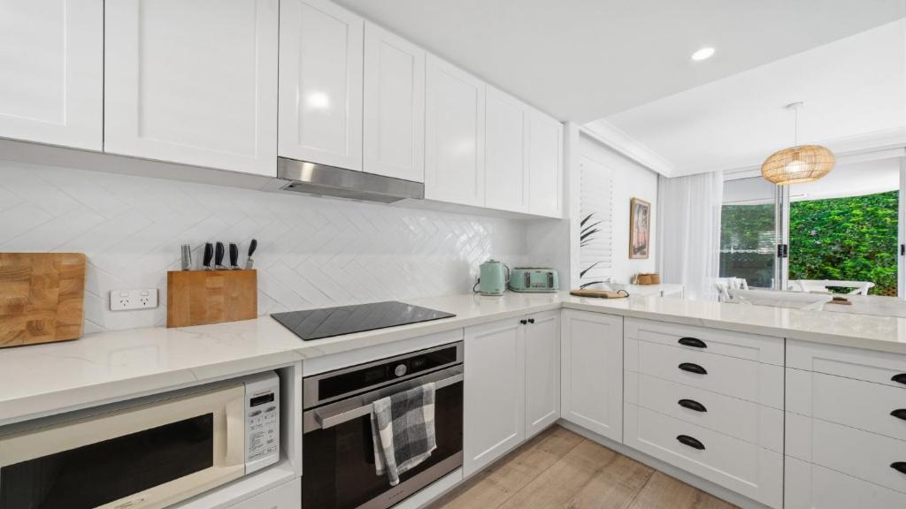 a white kitchen with white cabinets and a sink at Sea Glass in Terrigal