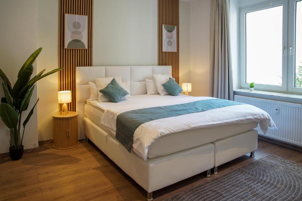 a bedroom with a large white bed with blue pillows at Bielefeld Grand Central Residence in Bielefeld