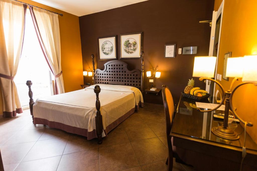 a bedroom with a bed and a table and a window at Hotel dei Coloniali in Siracusa