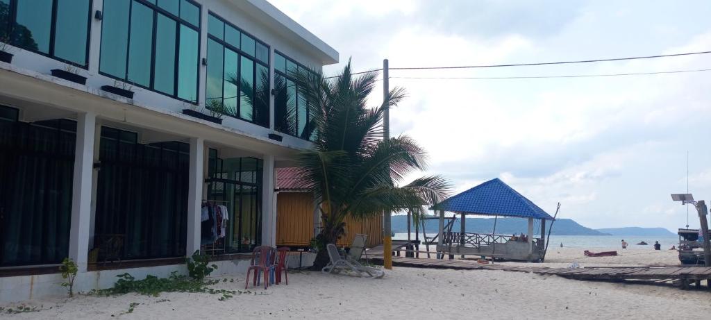 a building on the beach with a palm tree and a gazebo at water fall resort soksan in Phumĭ Kaôh Rŏng