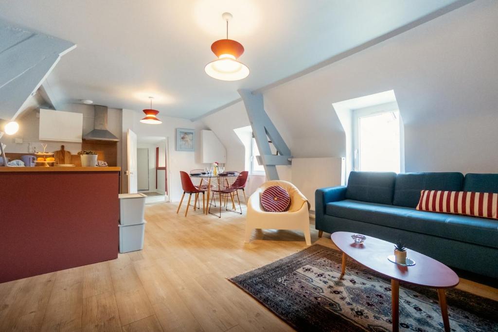 a living room with a blue couch and a table at Le Bleu et Rubis in Falaise