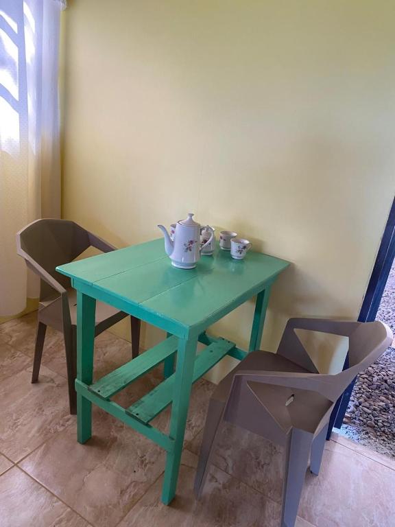 a green table with two teapots and two chairs at Una Mirada al Atardecer in Pedregoso