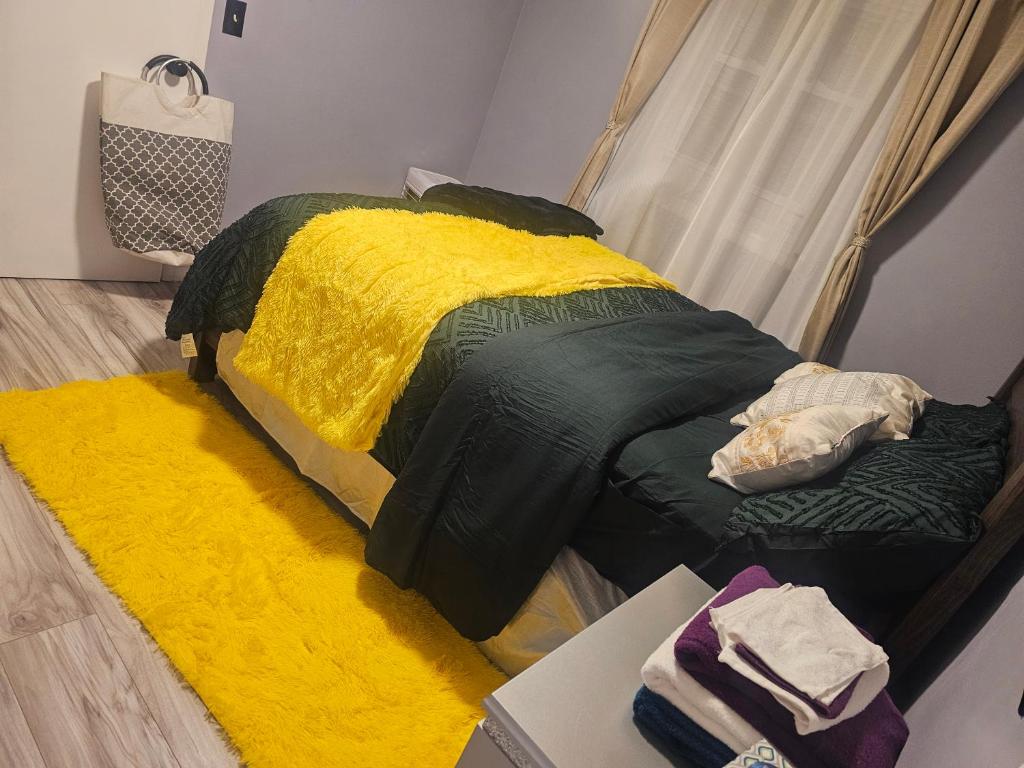 a bedroom with a bed with a yellow and green blanket at Cozy & Roomy Apt close to all in Orchard Park