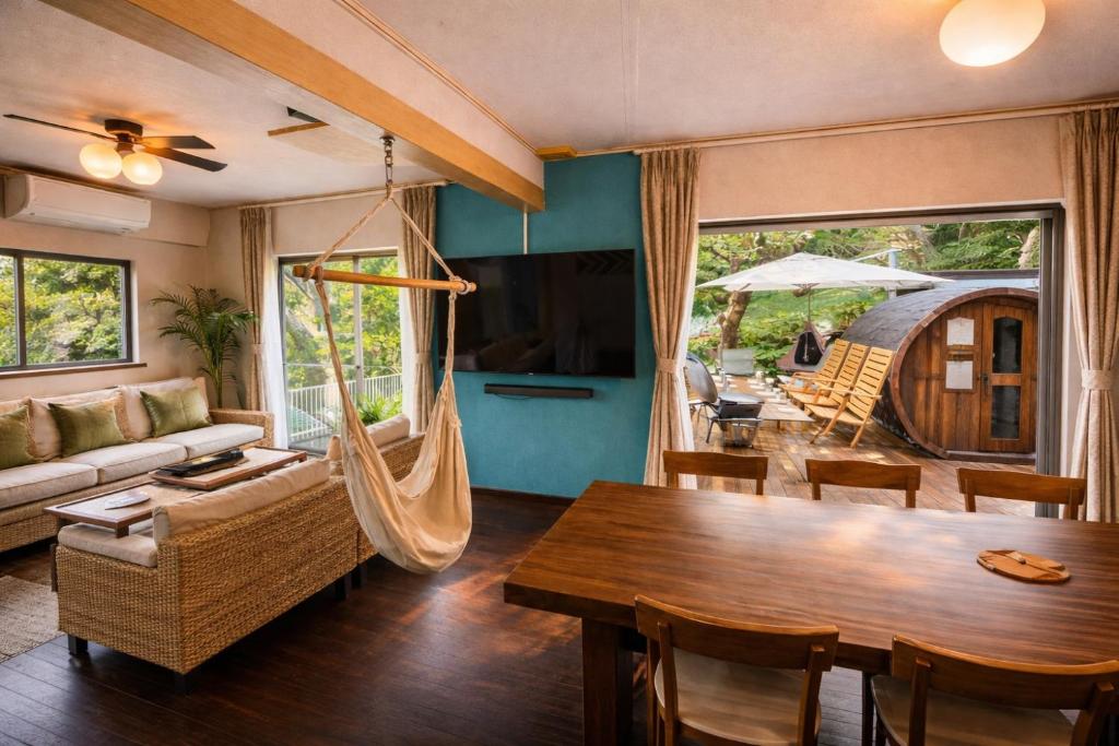 a living room with a table and a hammock at ゲストハウス三浦 サウナ Bbq 一棟貸し 最大13名 in Miura