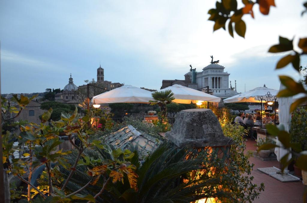 un giardino con tavoli e ombrelloni in città di Residenza Maritti Classic Rooms a Roma
