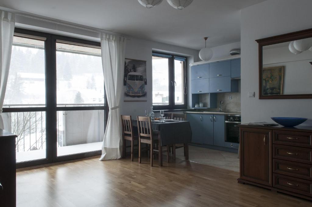 a kitchen with blue cabinets and a table with chairs at Apartament BB in Krynica Zdrój