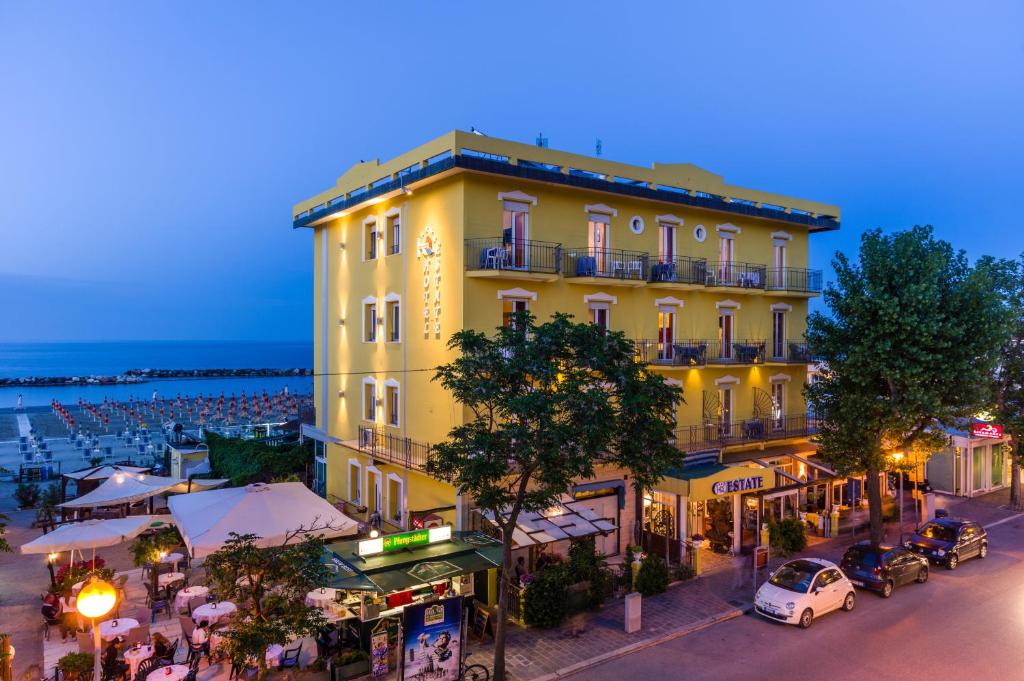 żółty budynek po stronie ulicy w obiekcie Hotel Estate w Rimini