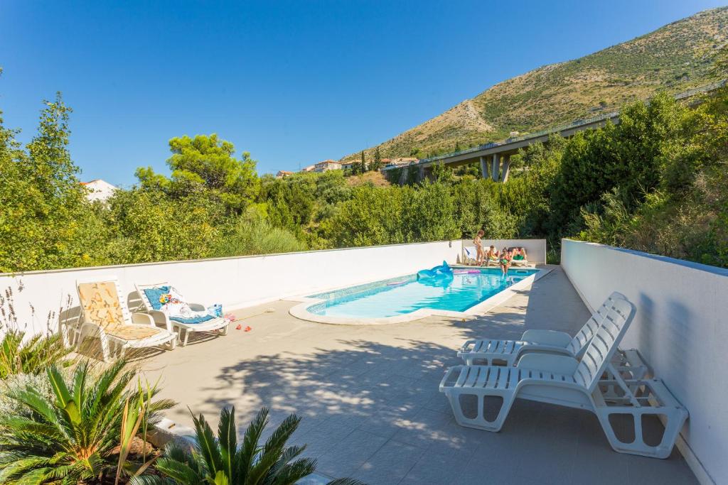 a patio with a swimming pool and two lounge chairs at Apartment Avoca in Cavtat