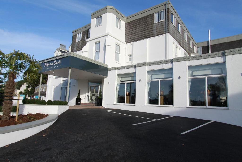 een wit gebouw met een parkeerplaats ervoor bij Belgrave Sands Hotel & Spa in Torquay