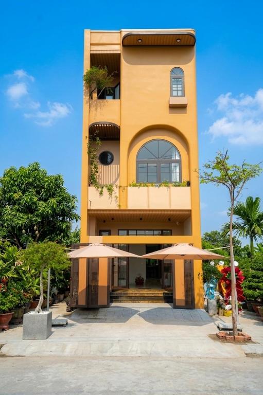 a yellow building with two umbrellas in front of it at AT Homestay Huế in Thôn Lại Thê