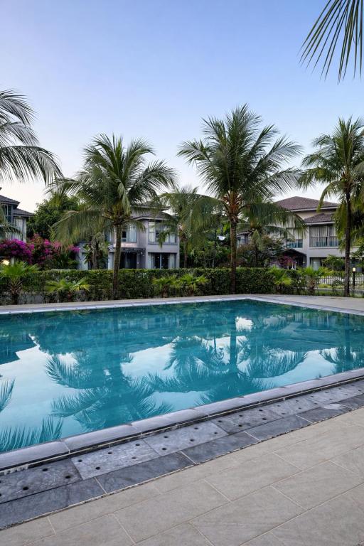 a large swimming pool with palm trees and houses at Luxury villa Phu Quoc in Phú Quốc