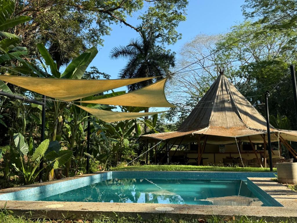 a resort with a pool and a thatch roof at KRITAJNA SAFARi LODGE in Dominical