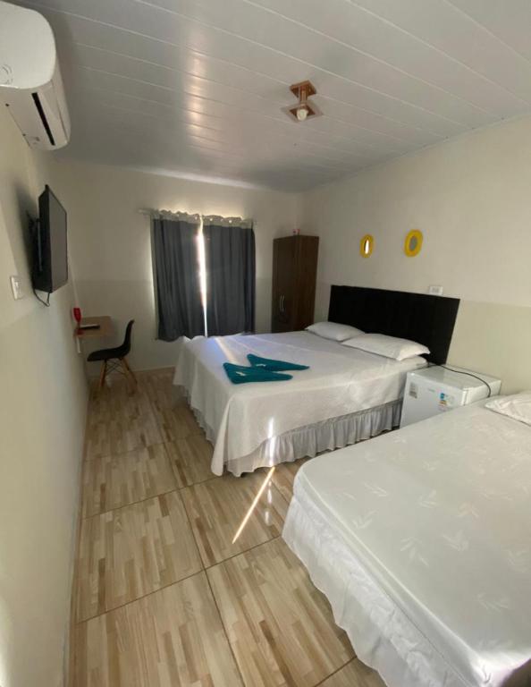 a hotel room with two beds and a tv at Belo Hotel in Ribas do Rio Pardo