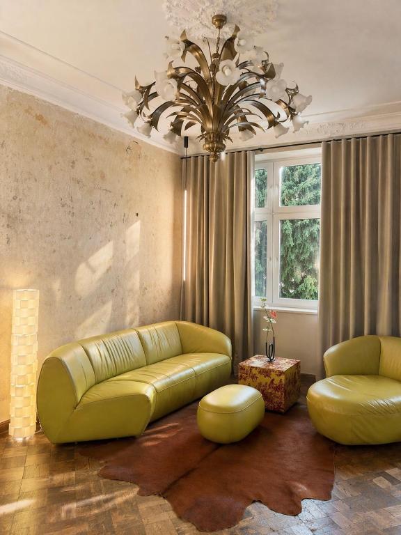 a living room with a yellow couch and a chandelier at Maison Stefana Rynek in Rzeszów