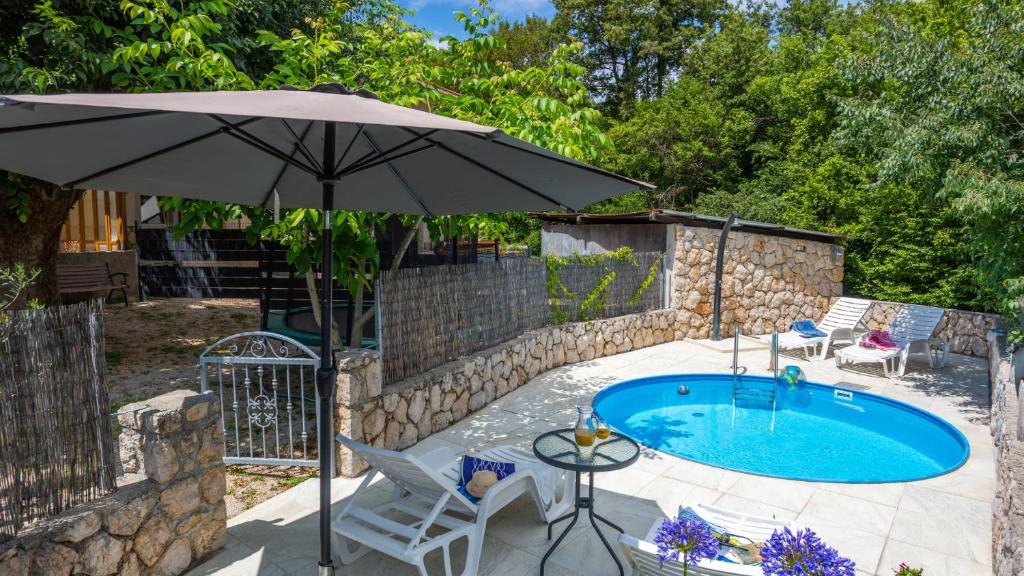 a patio with an umbrella and a swimming pool at Villa Risika 2 with pool island Krk by Villas Guid in Risika