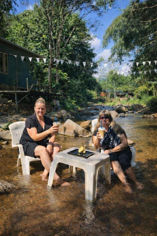 a group of women sitting in the water with drinks at 1000 Stars Riverside Hostel in Ban Khrae Yao Doi Bo