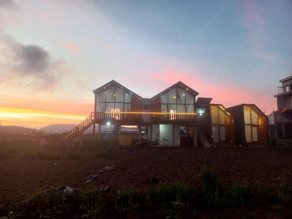 a house on a hill with the sunset in the background at Cabin Wetan Kali Dieng in Diyeng