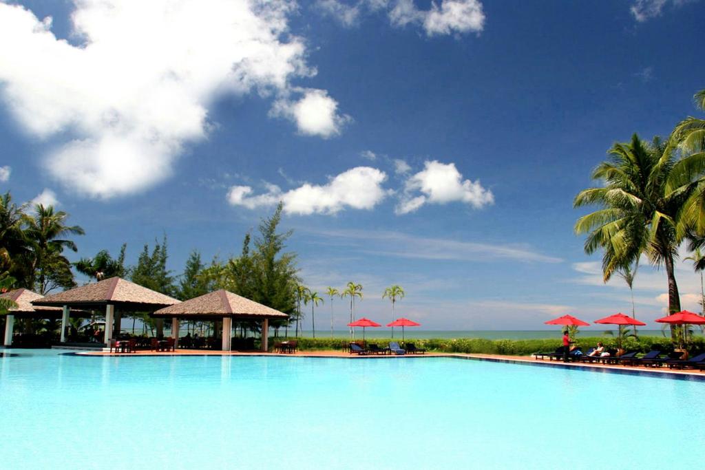 a large swimming pool with palm trees and umbrellas at Miri Marriott Resort & Spa in Miri