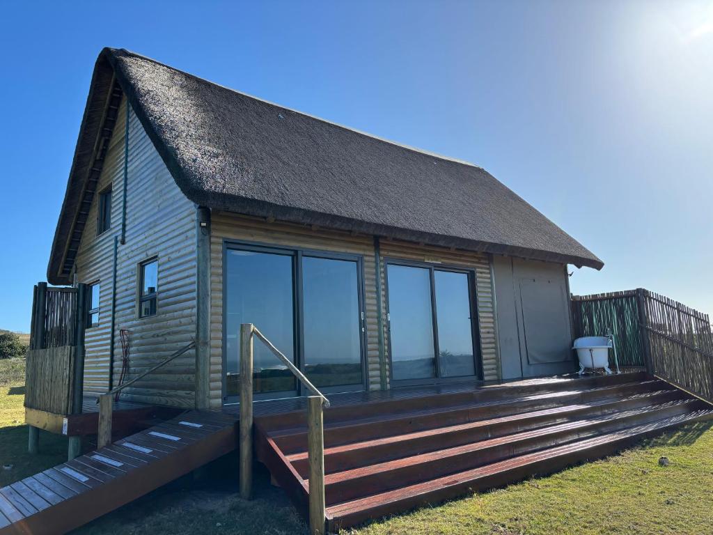 a cabin with a large deck and glass windows at Kuierbos in Gouritzmond
