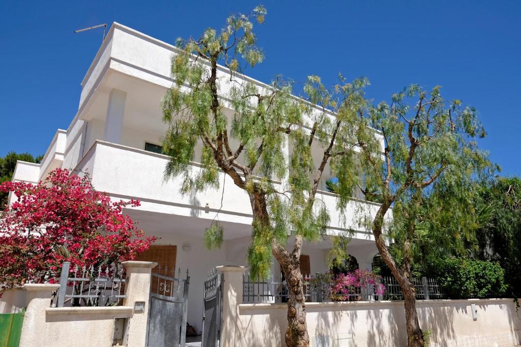 une maison blanche avec des arbres devant elle dans l'établissement Villa Marlene, à Torre Santa Sabina