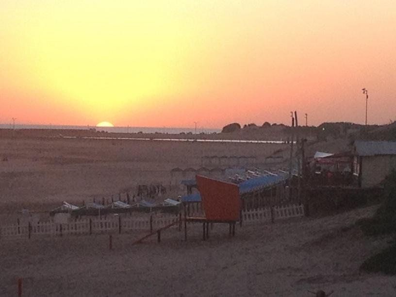 a sunset over a beach with a fence and the ocean at Pinocho in Puerto Quequén