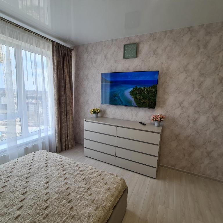 a bedroom with a bed and a tv on a wall at Апартаменты in Odesa
