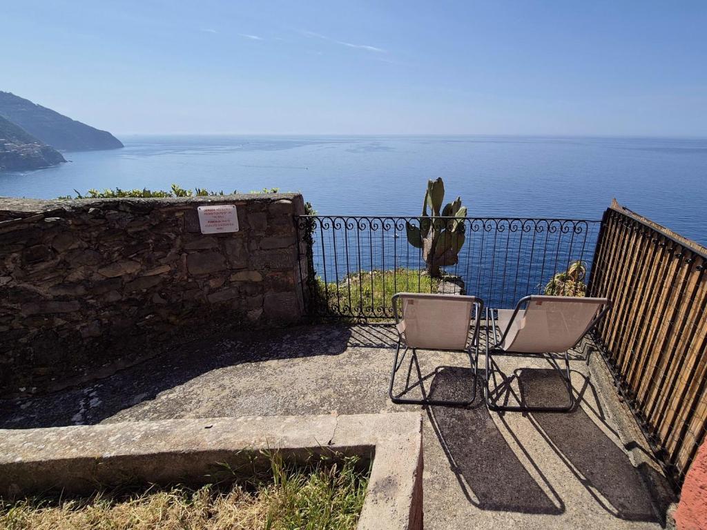 a couple of chairs sitting on a fence near the water at La Terrazza Sul Blu in Corniglia