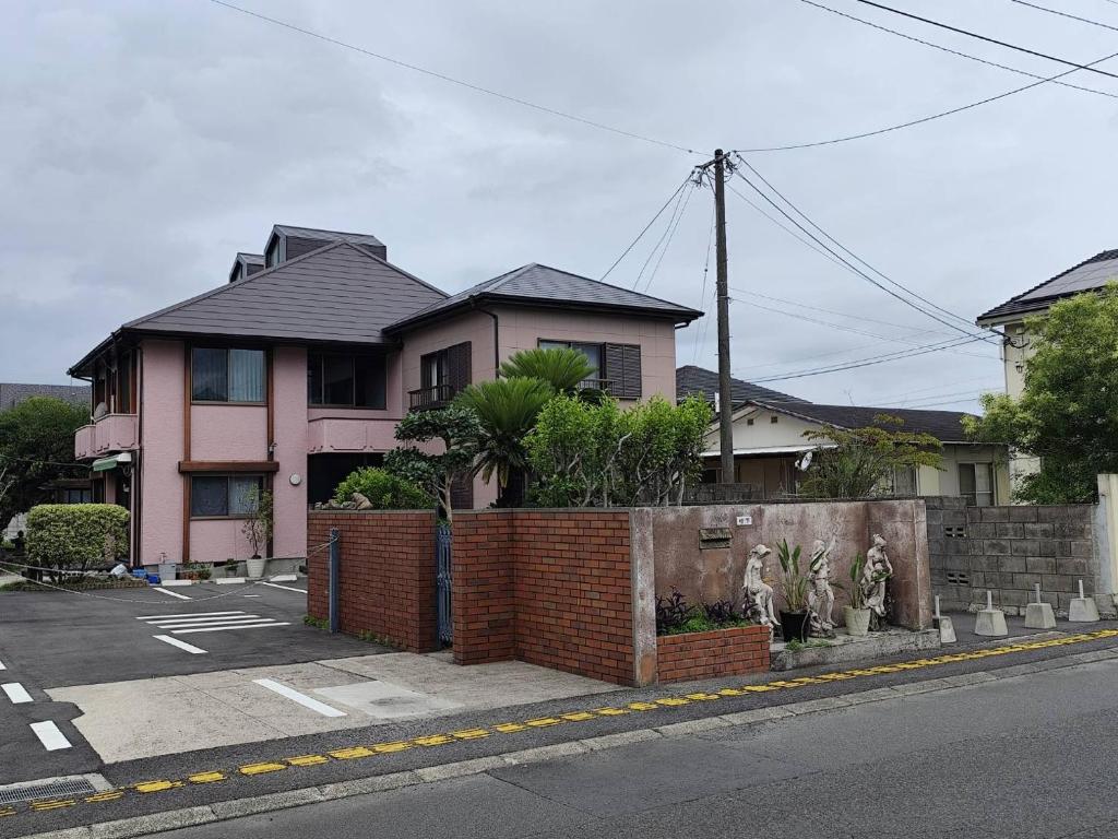 a pink house on the side of a street at 夢尽くし in Aira