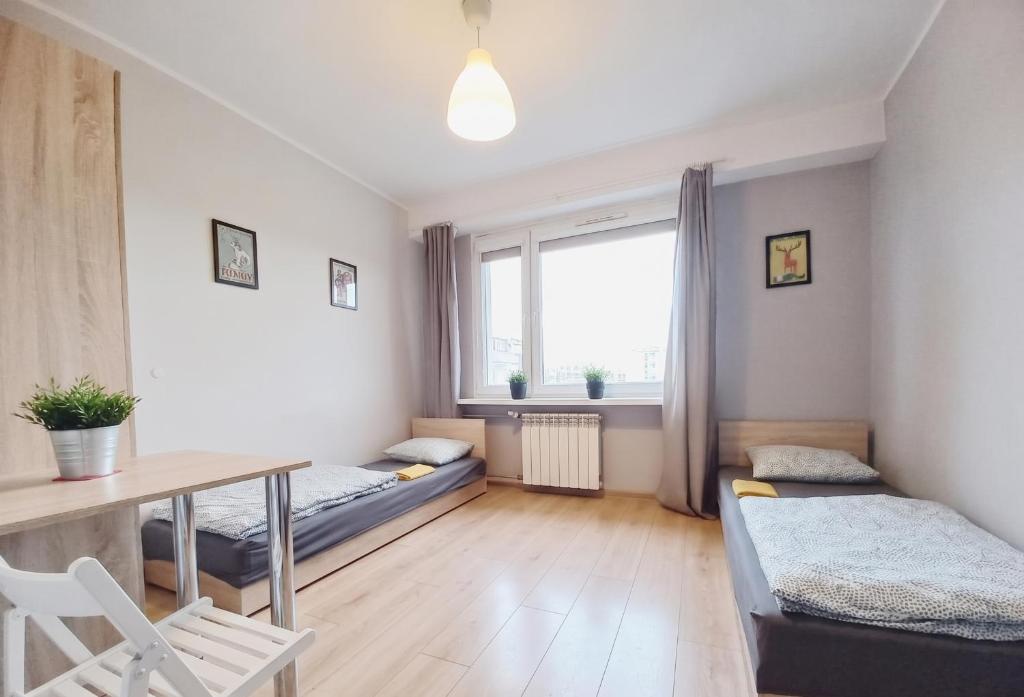 a small room with two beds and a table at Dobre Sny na Konopnej in Bydgoszcz