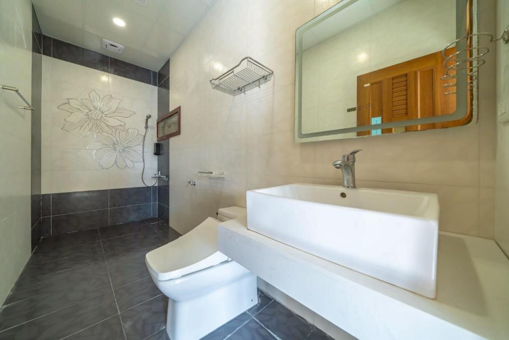 a bathroom with a sink and a toilet and a mirror at 伊旅旅宿民宿 in Guangfu
