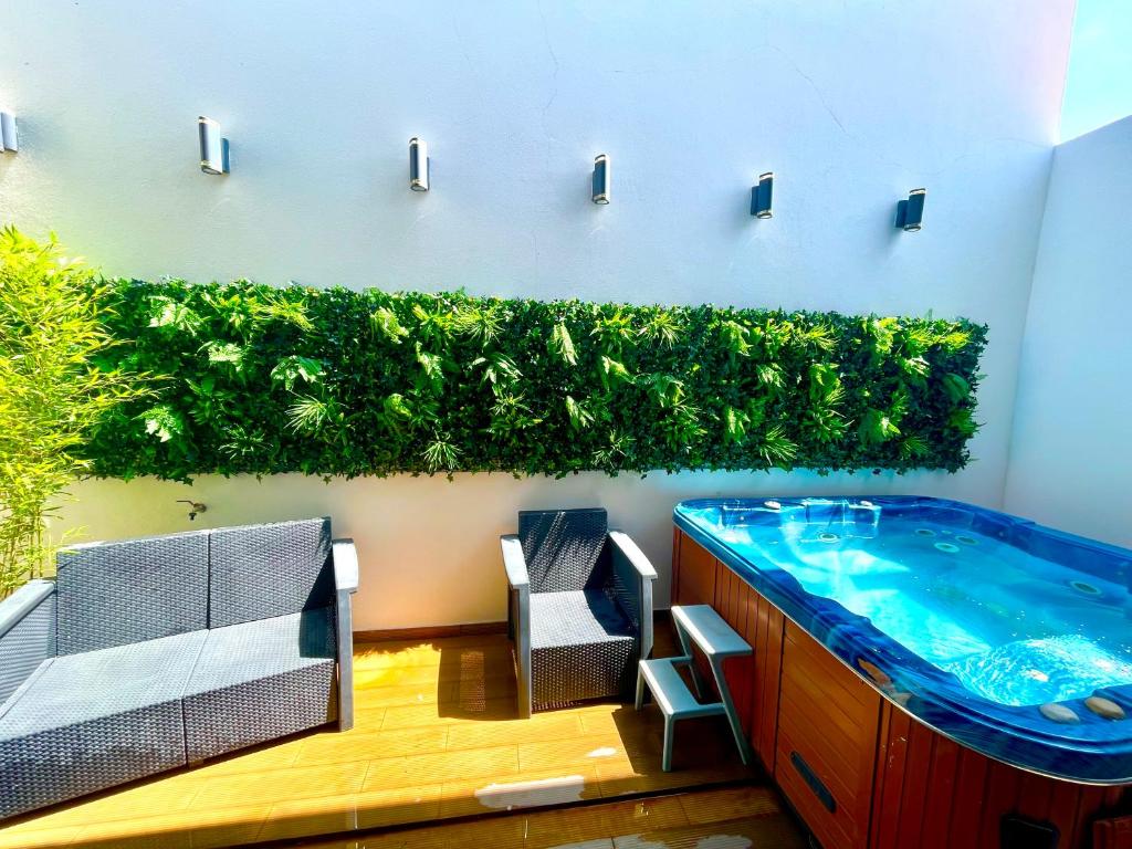 a bathroom with a jacuzzi tub with a green hedge at Private Hot Tub All Year Round - 25 min Lisbon in Setúbal