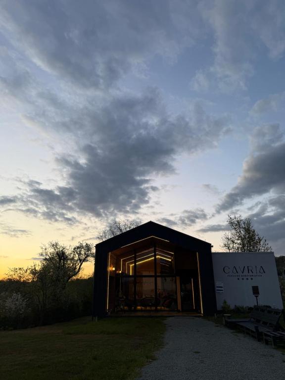 a building with glass windows and a cloudy sky at Cavria in Şurdeşti