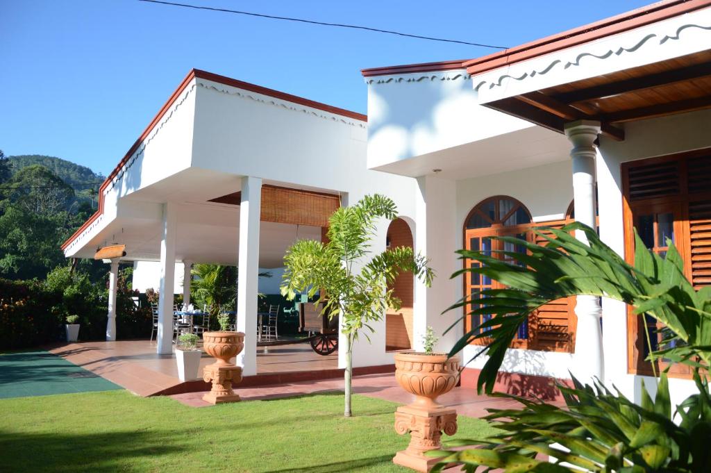 a white house with potted plants in a yard at Villa - Nil Vimana - Ella in Ella