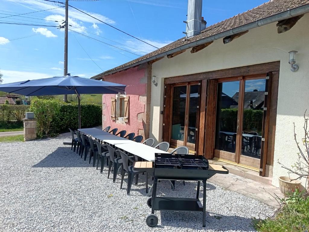 a long table with chairs and an umbrella at Gîte MARISA in Champagney
