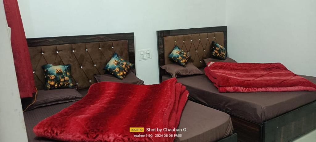 a room with two beds with red blankets and pillows at Hotel Mahadev in Sonprayag
