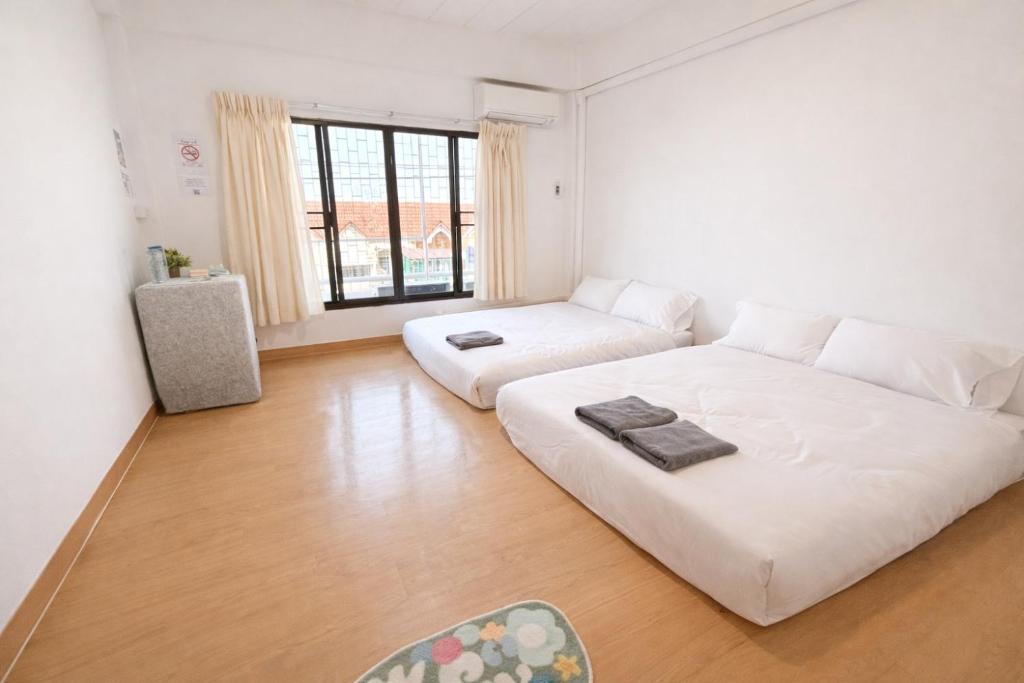 a living room with two white couches and a large window at The Layover Donmueang Airport Hostel in Thung Si Kan