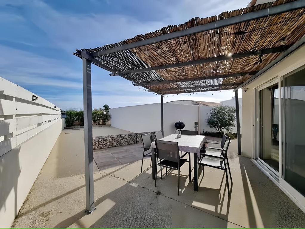 a patio with a table and chairs under a pergola at Le Boumian in Saintes-Maries-de-la-Mer