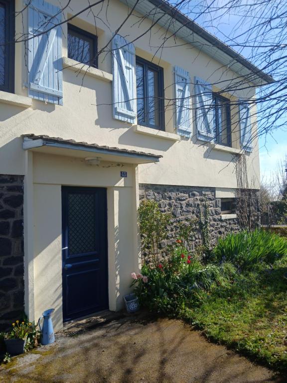 a white house with a blue door and windows at La maison aux volets bleus in Le Vigean