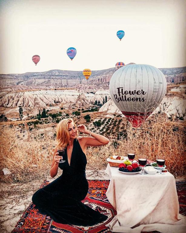 a woman sitting at a table in front of a table with balloons at Sevdalı Konakları in Avanos
