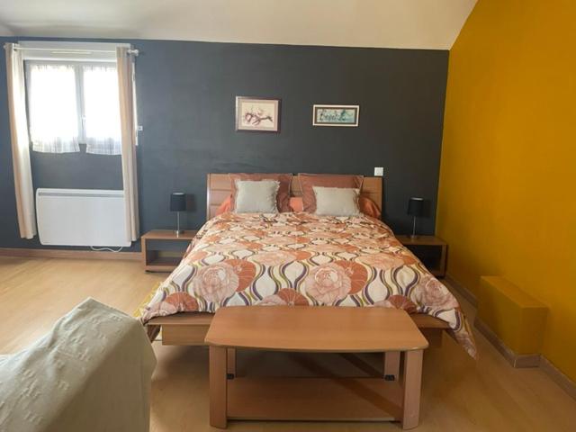 a bedroom with a bed and a table in it at La Suite Dorée à Amaryllis in La Guierche
